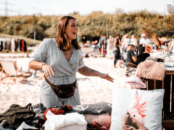Verkäuferin zeigt Ware auf dem Strandflohmarkt